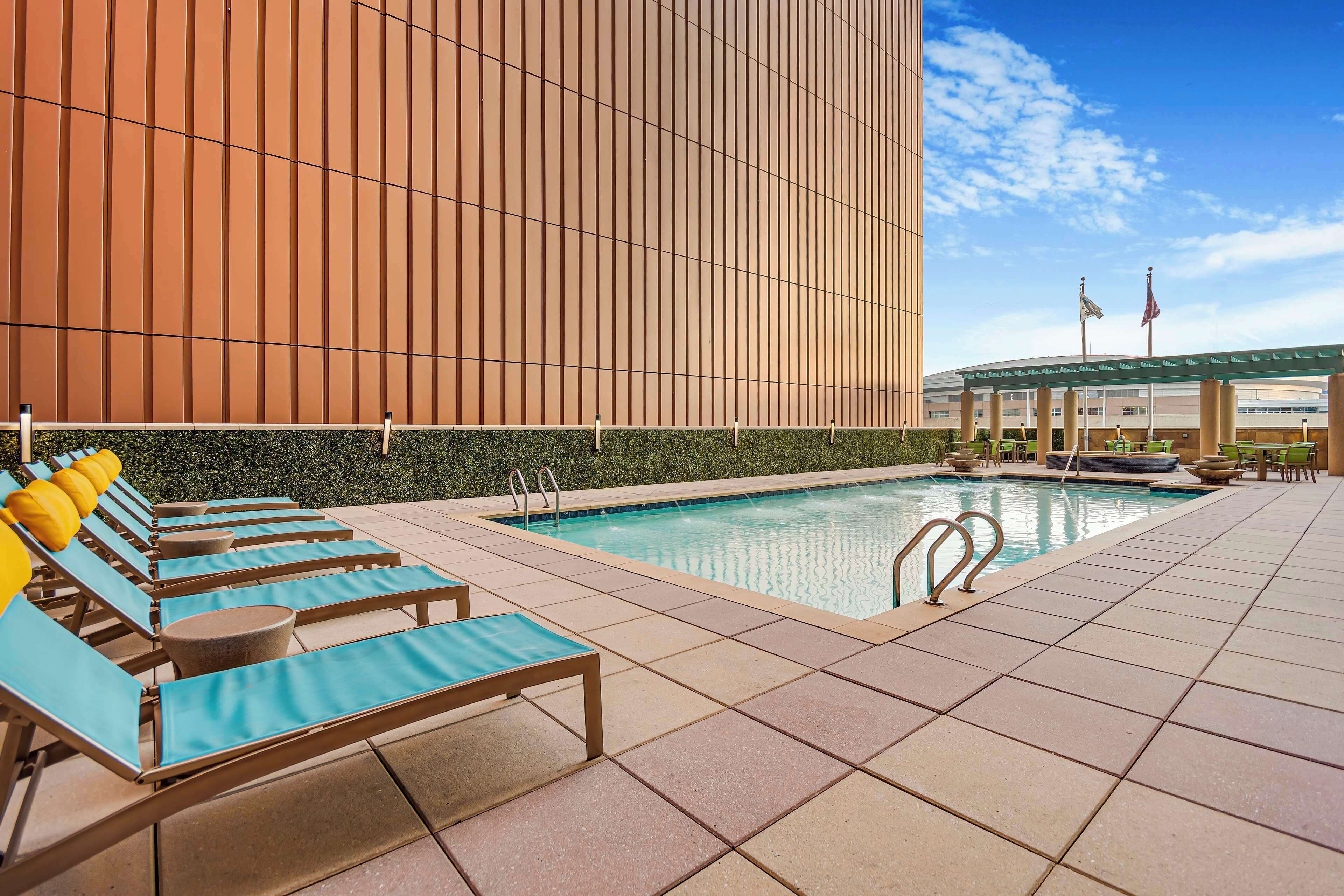 Zona de piscina con sillones de descanso y cielo despejado.
