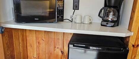 A compact kitchenette with a microwave, coffee maker, and a mini fridge.
