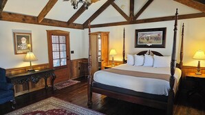 Un lit traditionnel à baldaquin, avec un sol en bois et un tapis rouge à motifs.