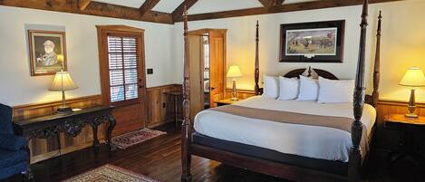 A traditional four-poster bed with a canopy, wooden flooring, and a red patterned rug.