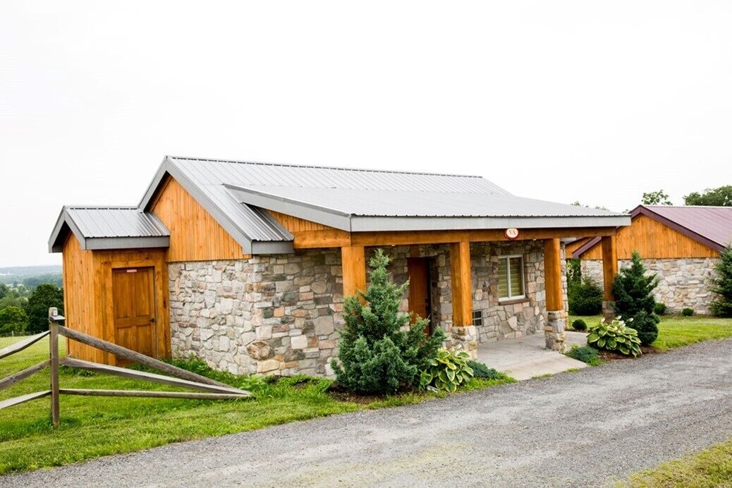 Una casa in pietra e legno con tetto in metallo, una porta di legno e un portico.