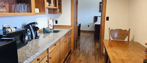 Una cocina con armarios de madera, encimera de granito y una mesa de comedor con sillas.