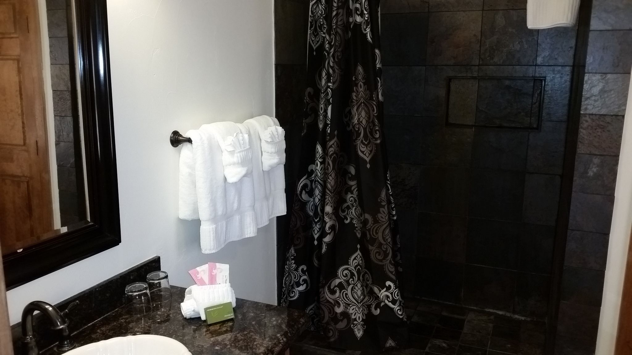 Une salle de bain avec une douche, un lavabo et un porte-serviettes avec des serviettes blanches.