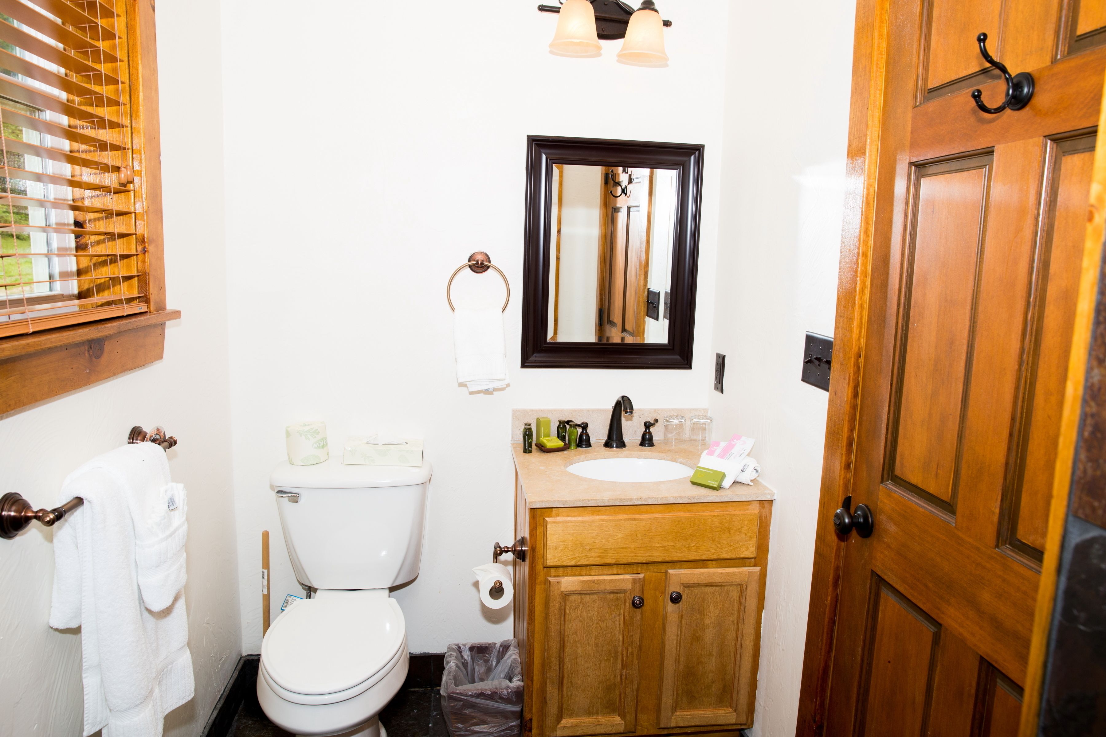 A compact bathroom with a toilet, sink, and mirror.