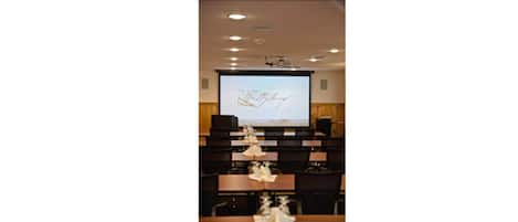 A conference room with a projection screen displaying 'The Lodge of Getting Married'.