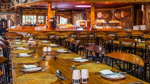Un restaurant doté de plusieurs tables, chacune mise avec des couverts, des assiettes et des serviettes.