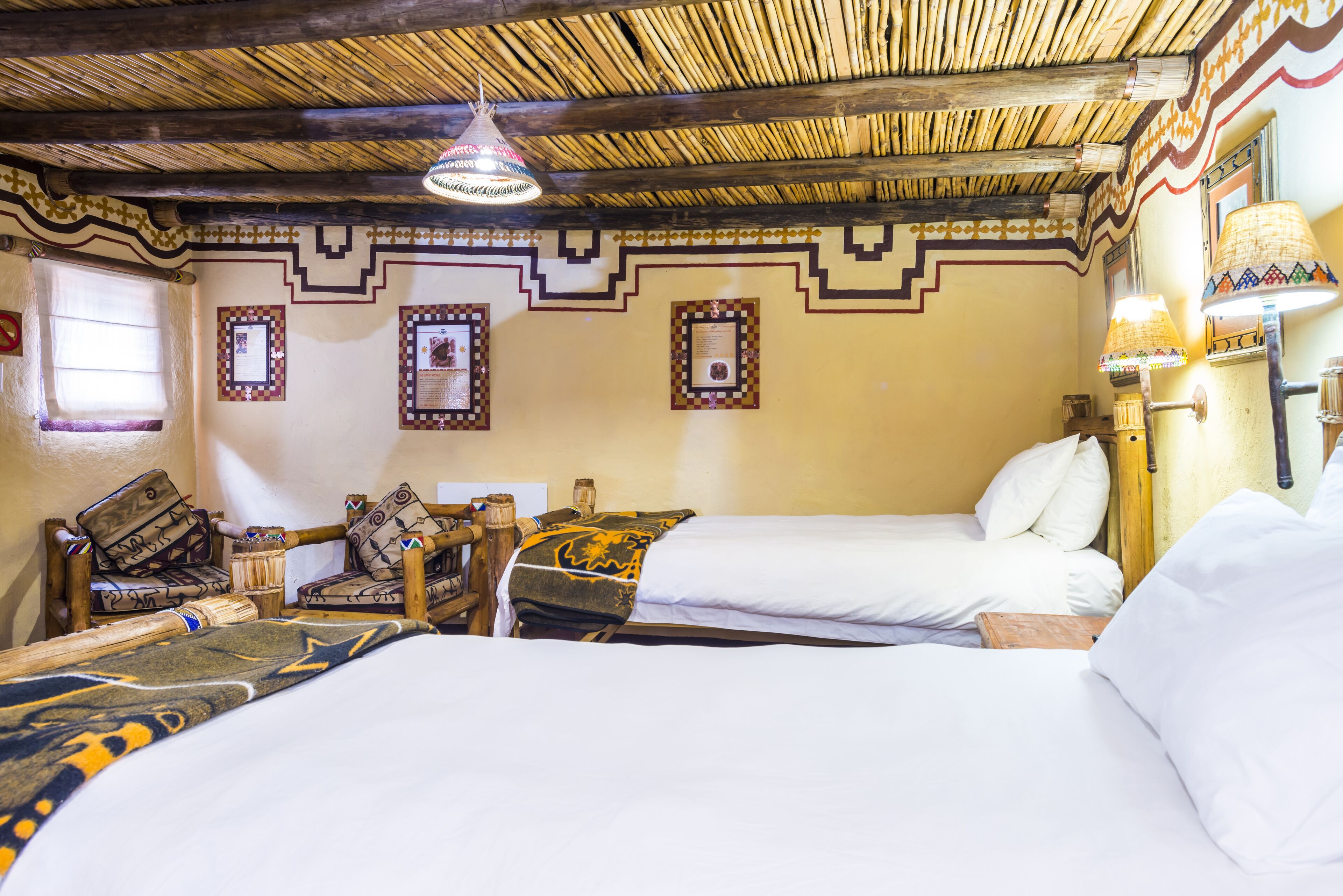 A room with two beds, wooden furniture, and decorative wall patterns.