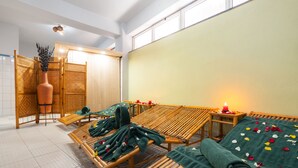 A spa room with wooden loungers, a large mirror, and a candle on a side table. - Beer Garden Inn (Addis Ababa)