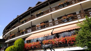 A multi-story building with balconies adorned with flower boxes and a deer statue in the foreground. - Centro Vacanze Veronza Clubresidence (Ville di Fiemme)