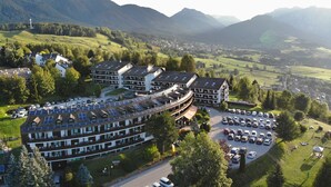 A hotel with a curved roof, solar panels, and a parking lot. - Centro Vacanze Veronza Clubresidence (Ville di Fiemme)