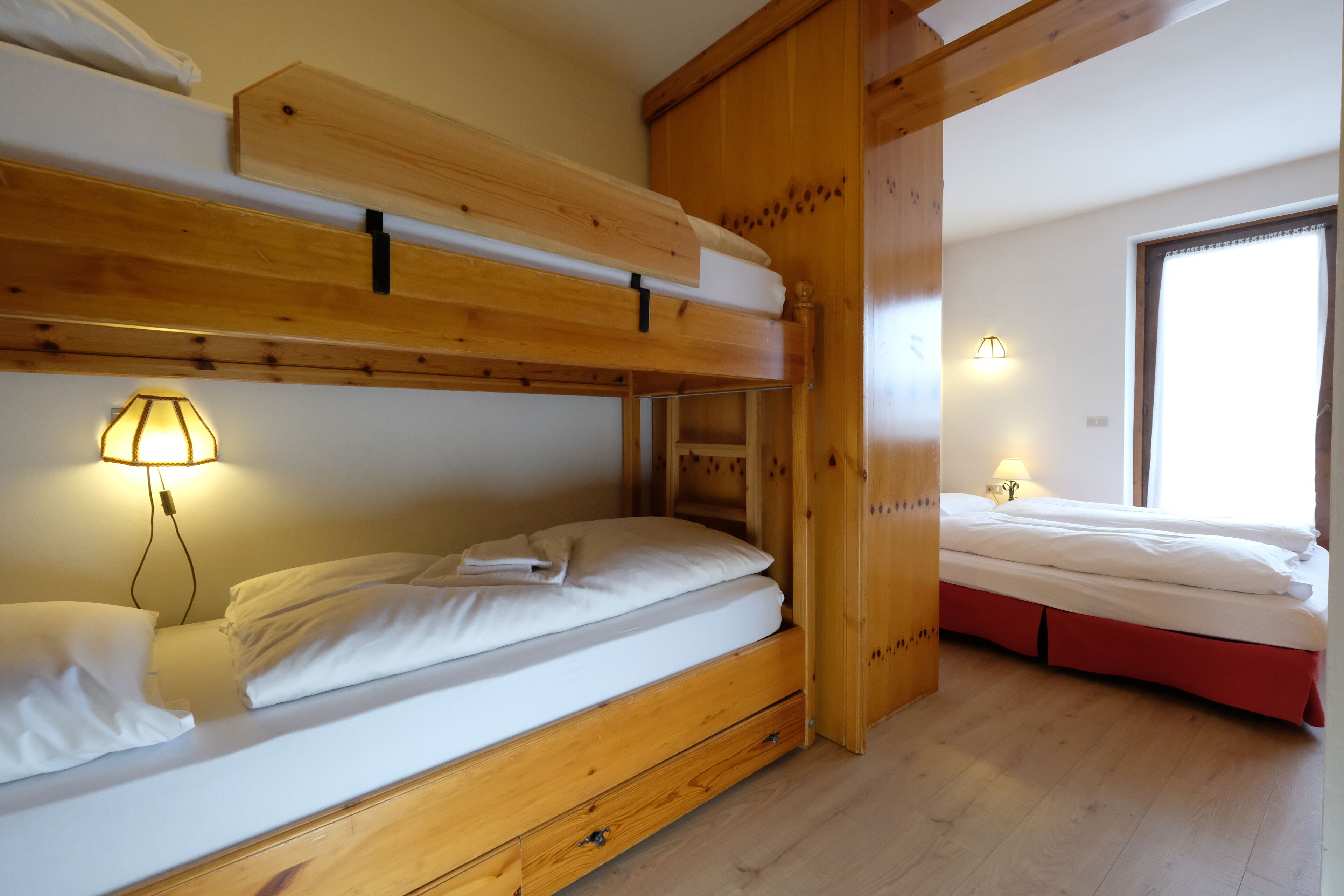A room with two bunk beds, wooden headboards, and a window with a view.