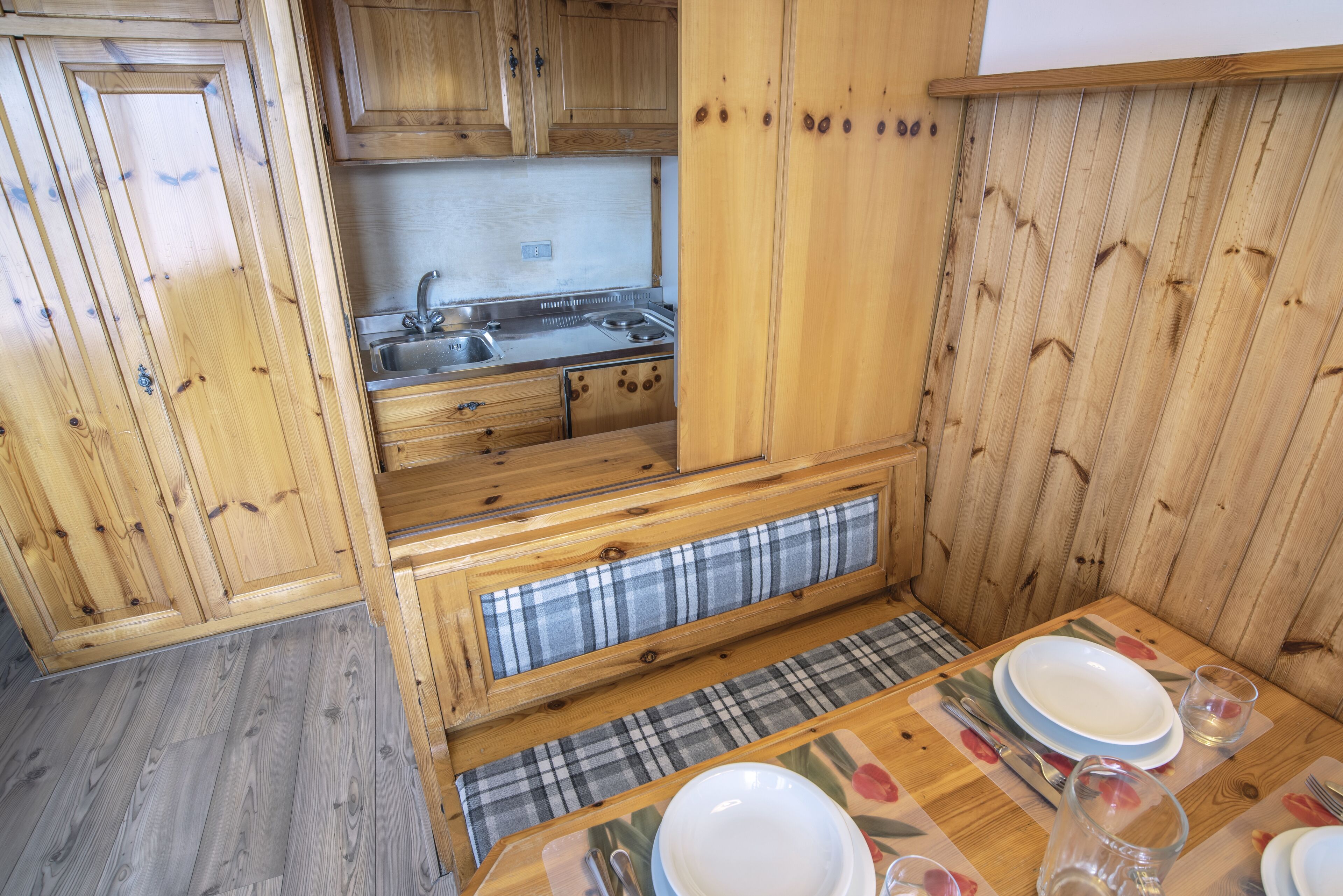 Una cocina de madera con estufa integrada, pileta y armarios superiores.
