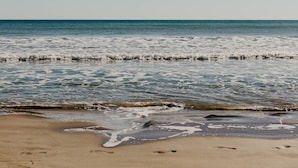 Een strand met heldere lucht en rustig water.