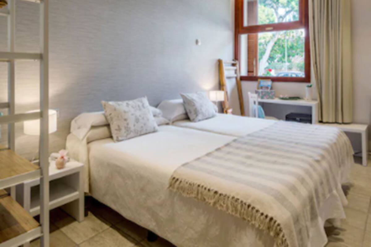 Un dormitorio con cama, mesitas de noche, un escritorio y una ventana con cortinas.