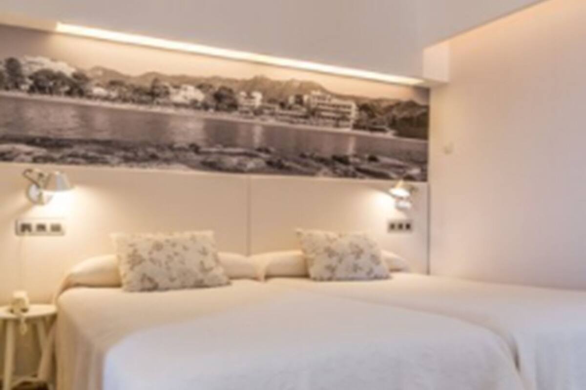 Un dormitorio con cama, mesitas de noche y una repisa en la pared.