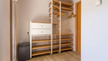 A walk-in closet with open shelving, a small desk, and a trash bin.