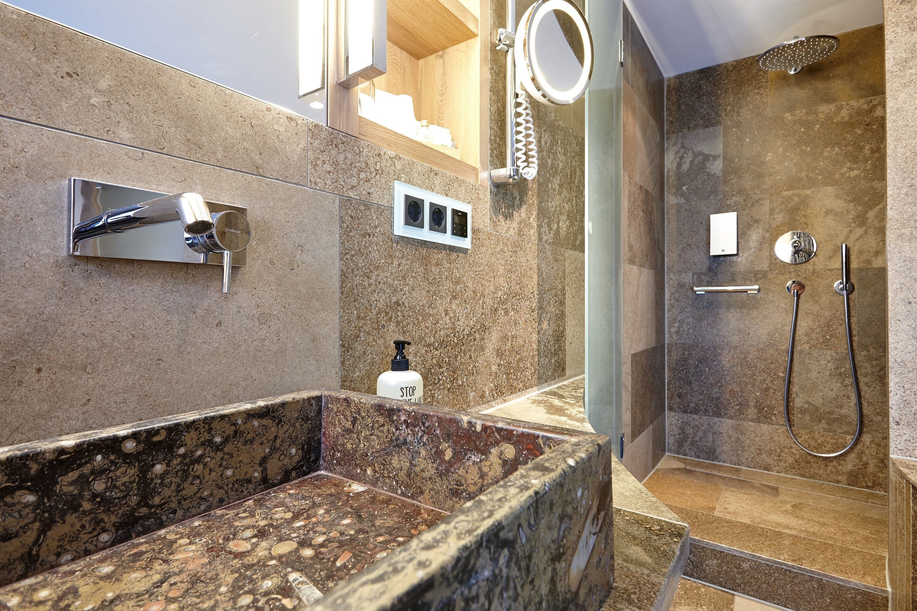 Un baño moderno con lavabo de granito, ducha de mano y inodoro integrado.