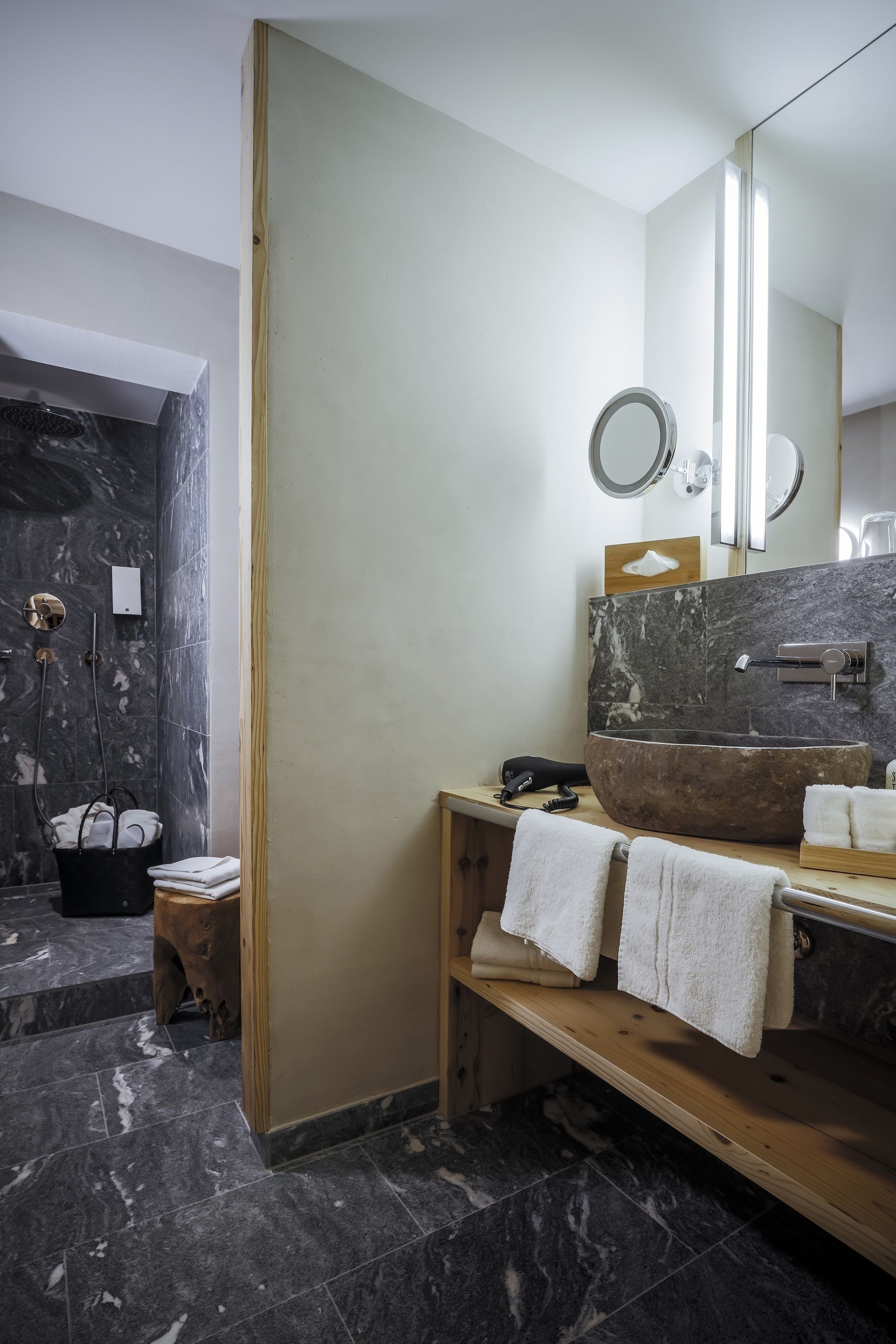Une salle de bain moderne avec un grand meuble-lavabo en bois, un lavabo en pierre et un miroir.