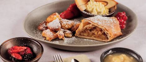 A plate with pastries, berries, and a small bowl of cream.
