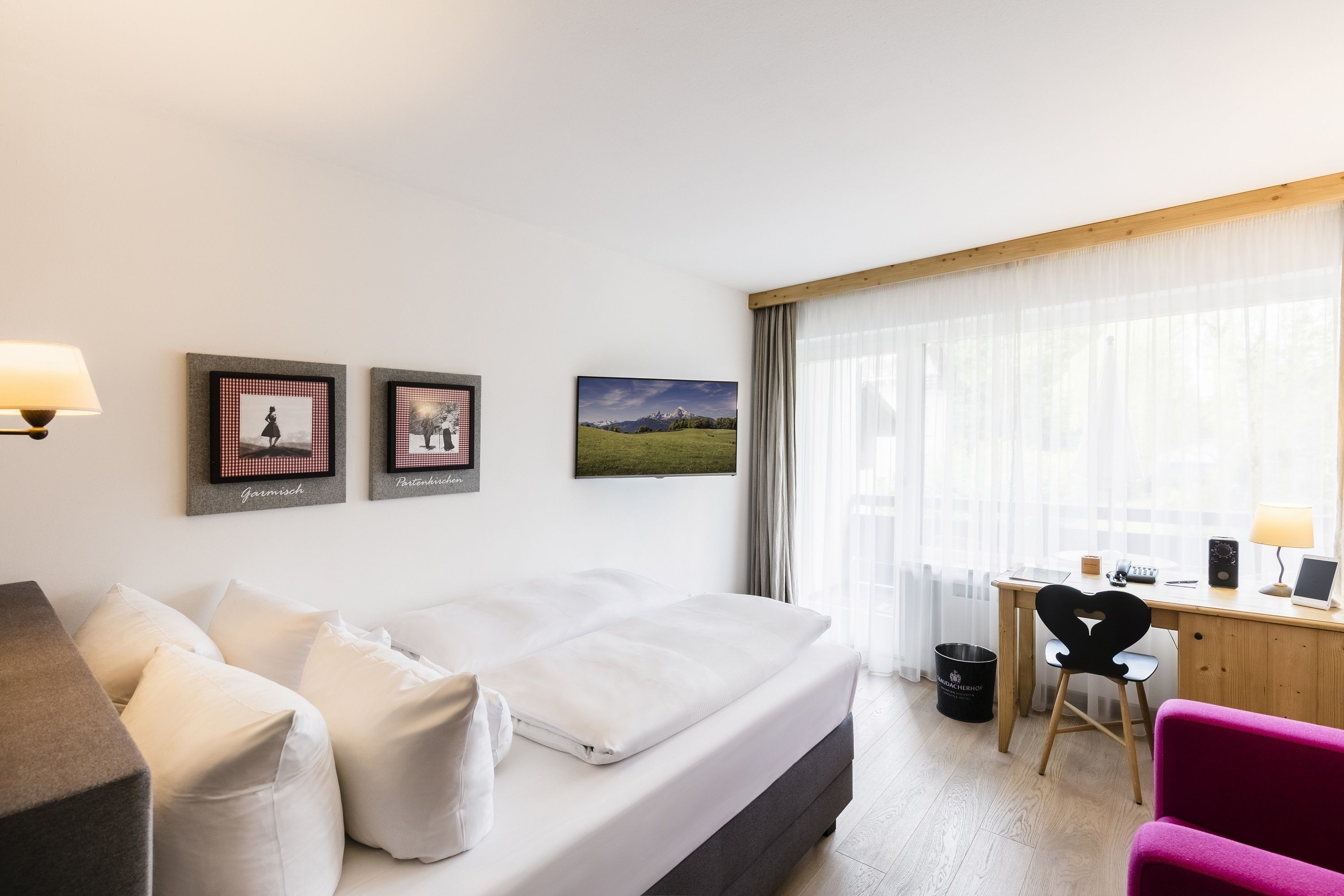 Ein Hotelzimmer mit Bett, Schreibtisch, Stuhl und einem Fenster mit Vorhängen.