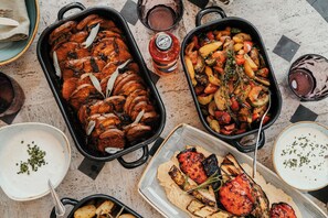 Una variedad de platos que incluyen carnes asadas, verduras y salsas, dispuestas sobre una mesa.