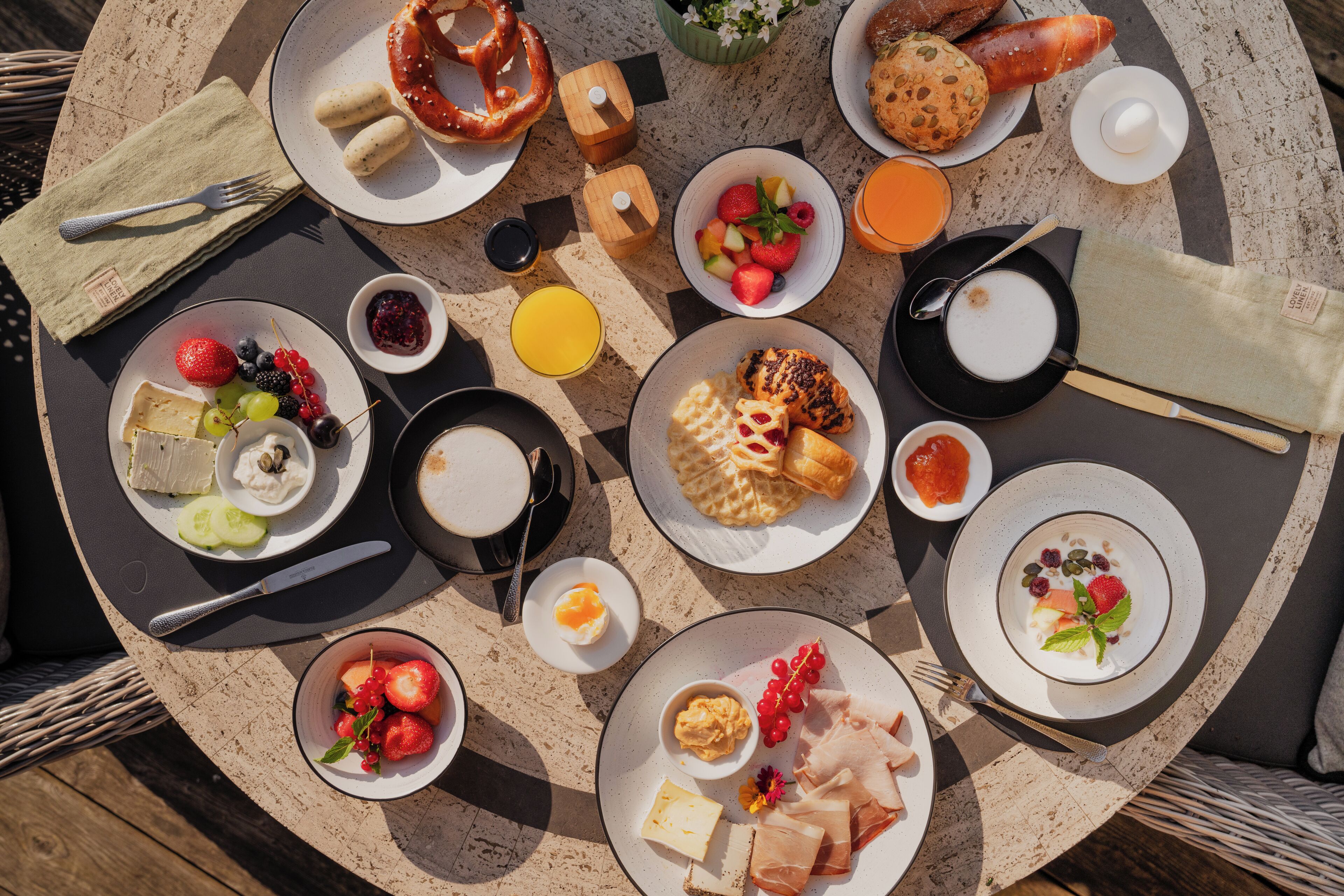 A round table with various breakfast items including fruits, pastries, and cheese.