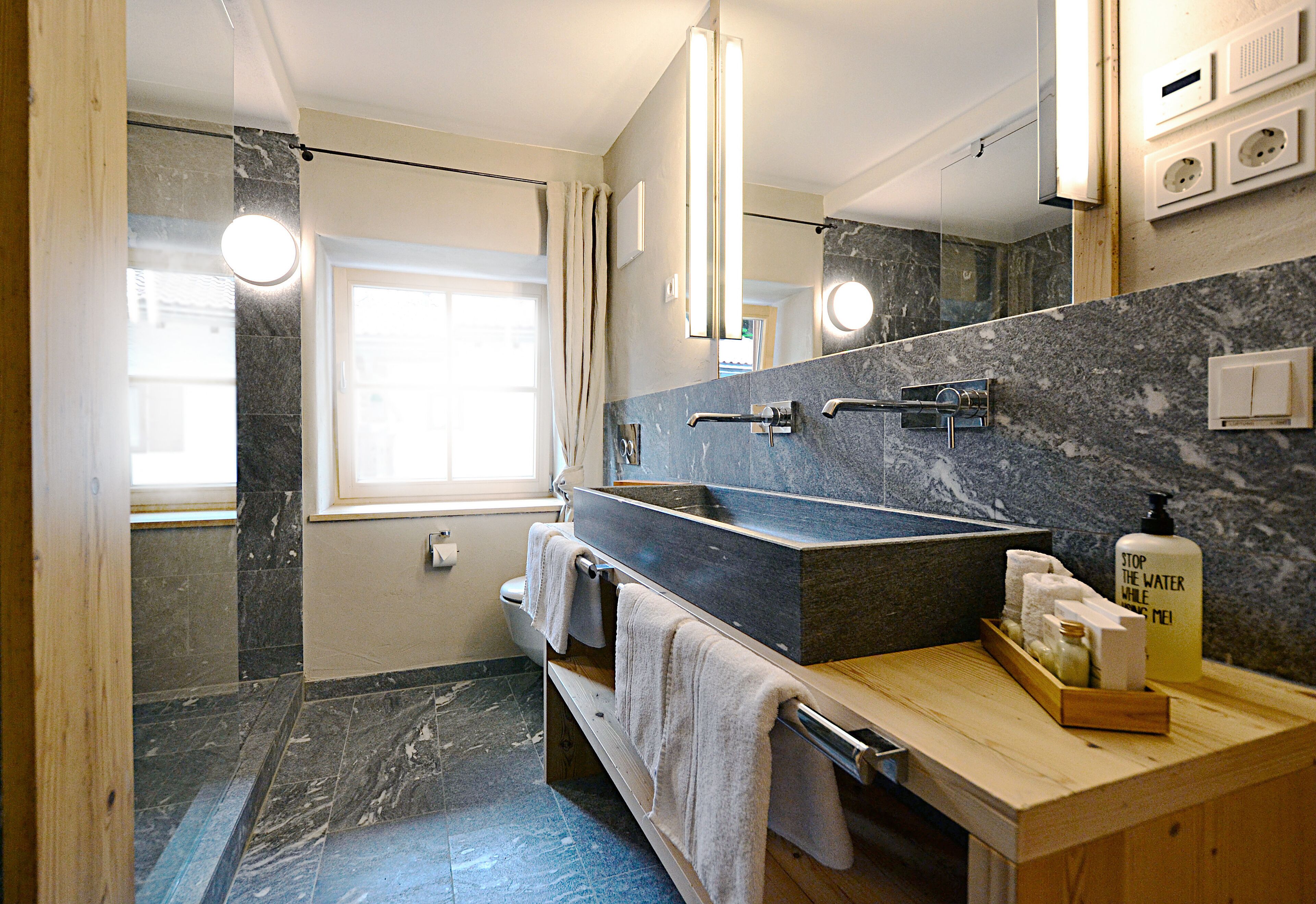 A modern bathroom with a large sink, mirror, and towel rack.