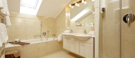 A modern bathroom with a skylight, a bathtub, a shower, and a vanity with a mirror.