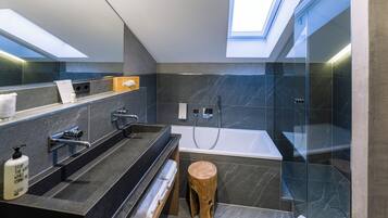 A modern bathroom with a skylight, a bathtub, and a vanity with a mirror.