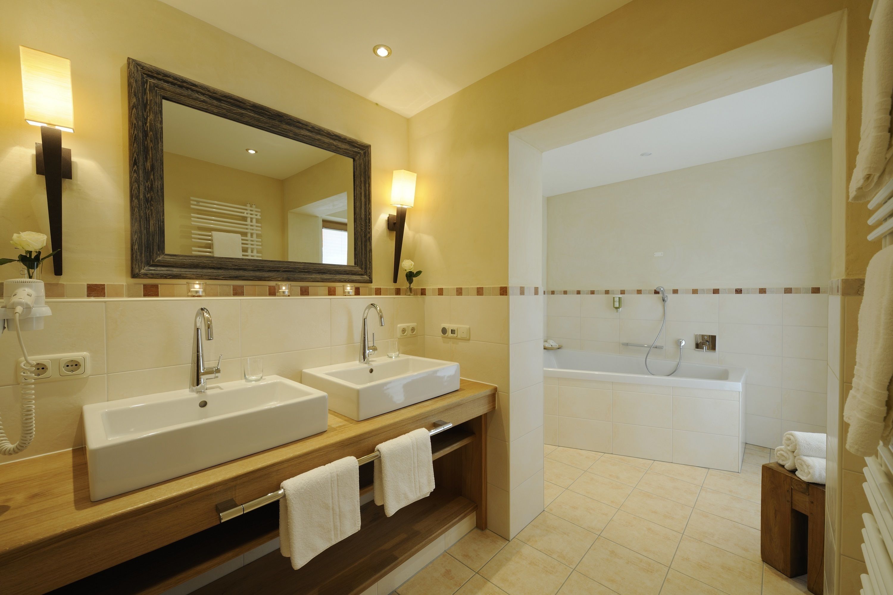 Un baño moderno con dos lavamanos, un espejo grande y una bañera.