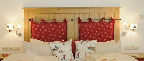 A double bed with white bedding and red curtains with a ski pattern.