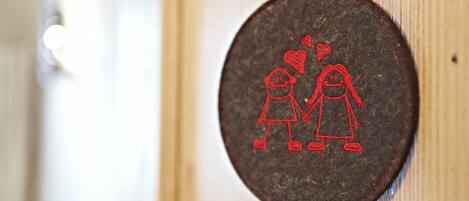 Tapiz circular con borde rojo, que muestra dos figuras tomadas de la mano y un corazón entre ellas.