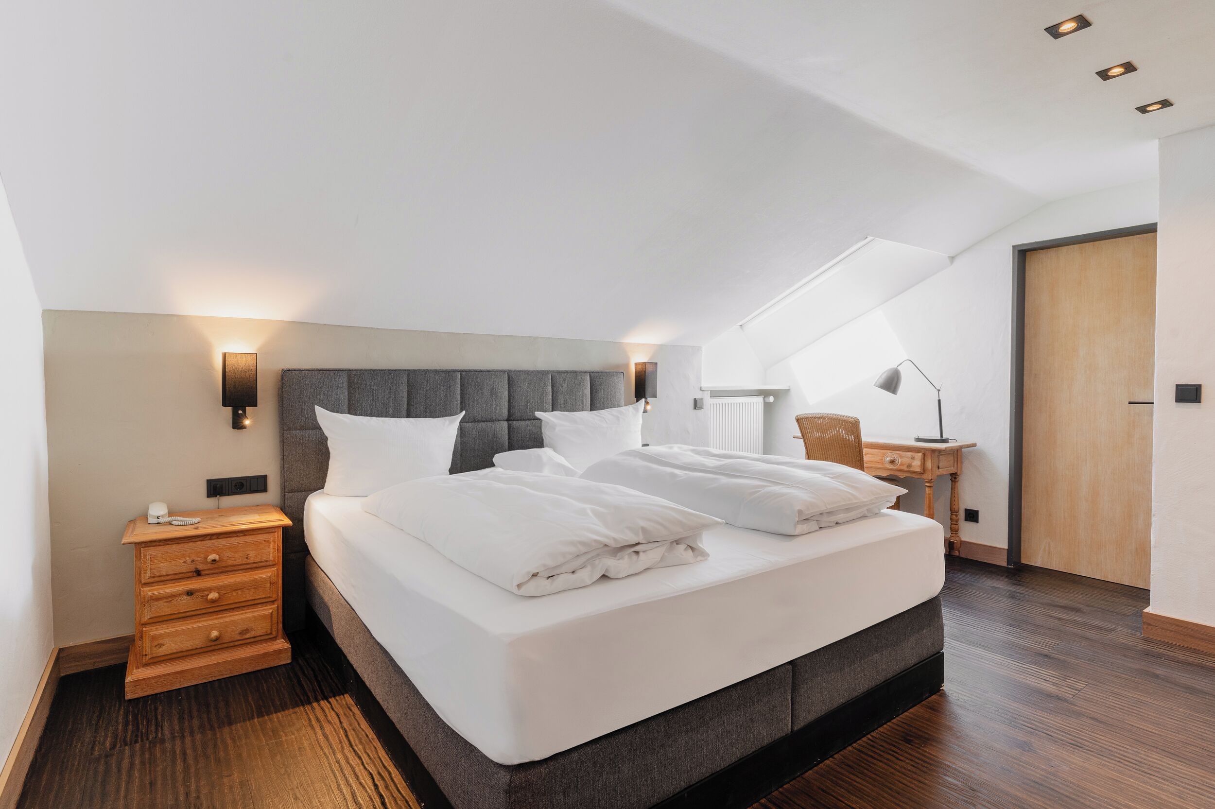 Une chambre moderne avec un grand lit, des lampes de chevet, une table de chevet et un bureau avec une chaise.