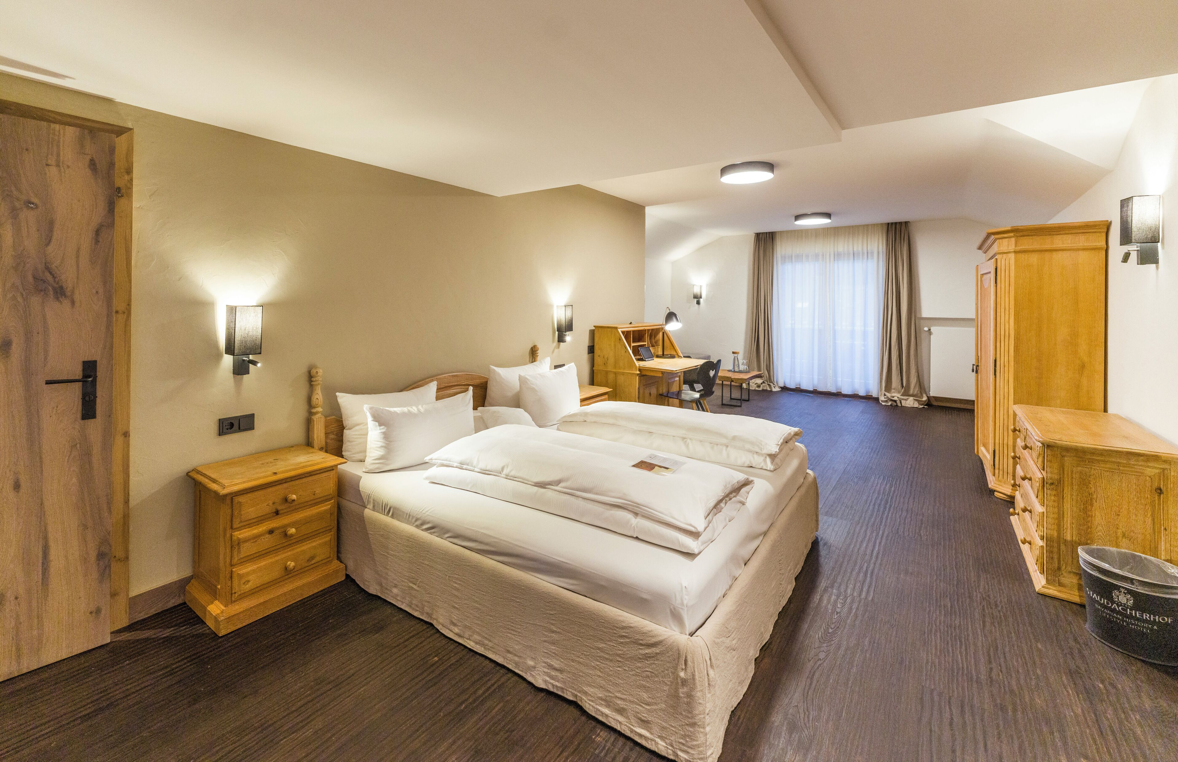 Ein Hotelzimmer mit einem großen Bett, Nachttischen, einem Schreibtisch und einem Kleiderschrank.