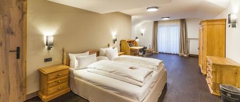 A hotel room with a large bed, bedside tables, a desk, and a wardrobe.
