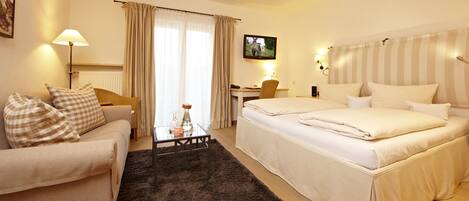 A hotel room with a bed, a desk, a chair, a sofa, and a lamp.