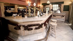 A bar area with a marble counter, multiple wine bottles, and stools. - Casa Palacio Pilar del Toro (Granada)