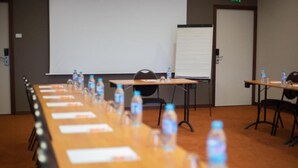 Een vergaderzaal met een lange tafel, stoelen, waterflesjes en een whiteboard.