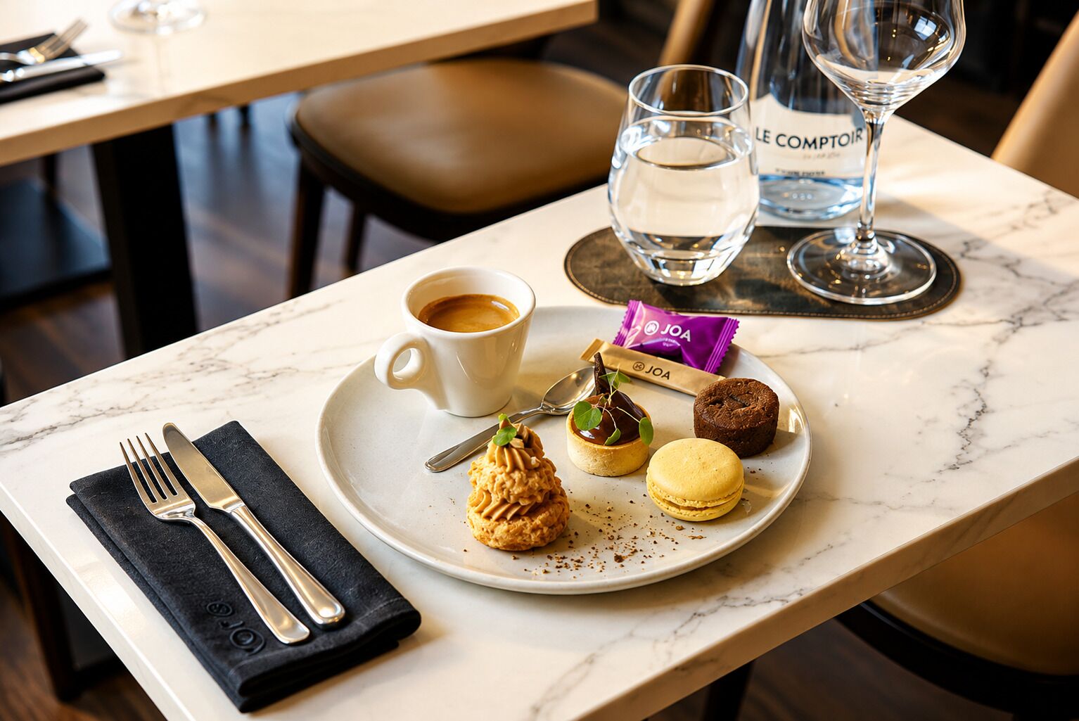 A dining table with a plate of food, a cup of coffee, a glass of water, and a bottle of water.