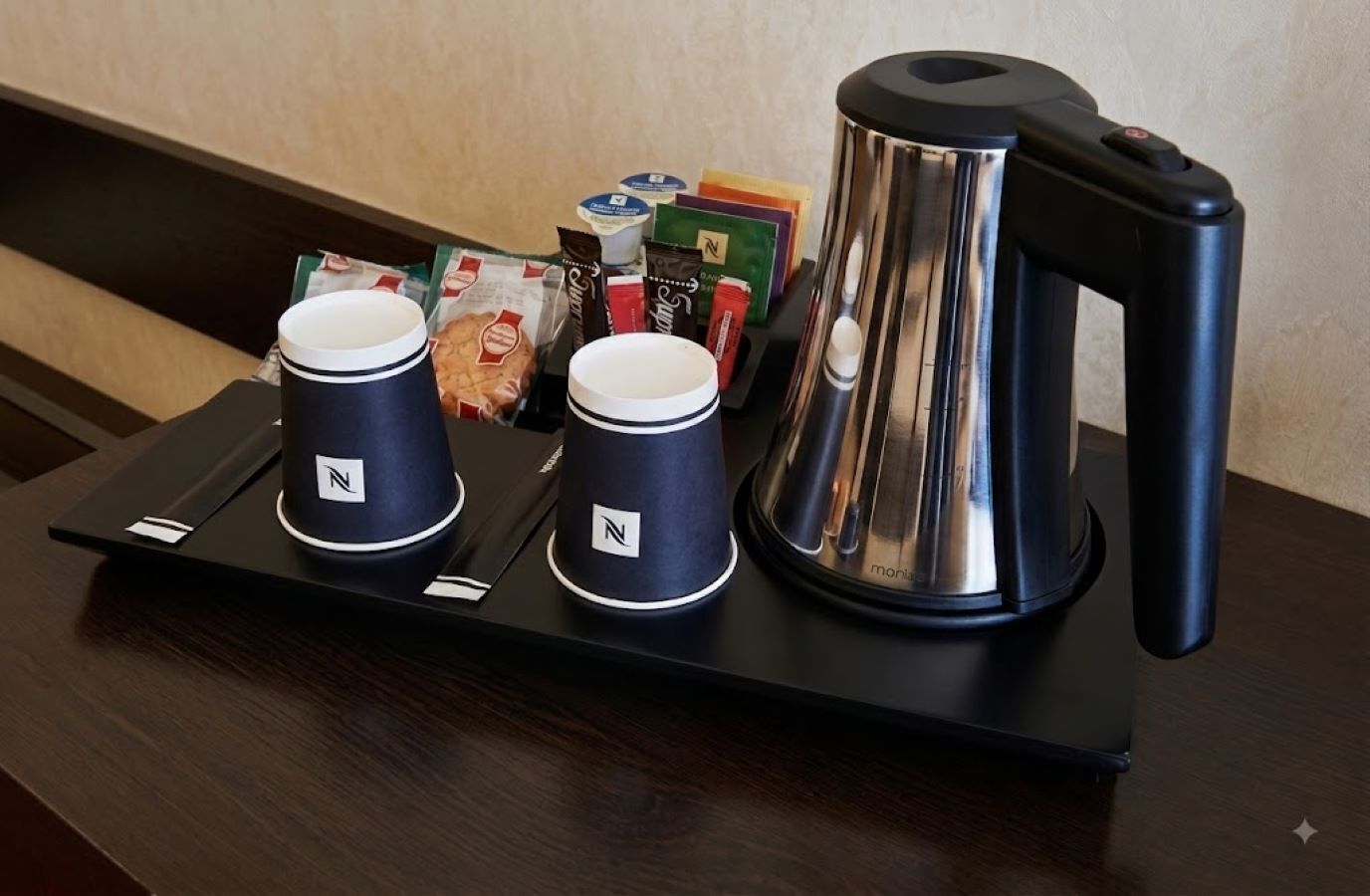 Un plateau avec deux tasses de café et une bouilloire, posé sur une table.