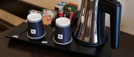 A tray with two coffee cups and a kettle on a table.