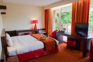Une chambre d’hôtel avec un lit, un bureau, une télévision et un balcon avec des rideaux.