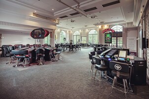 Una sala amplia con varias mesas y sillas para juegos, una ruleta y un cartel que indica un juego de ruleta.