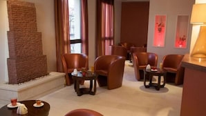 Eine Hotelhalle mit Ledersesseln, einem Kamin und Kunstwerken an den Wänden.
