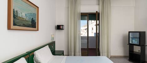 Una camera d'albergo con un letto, un quadro, una televisione e una vista attraverso una porta.