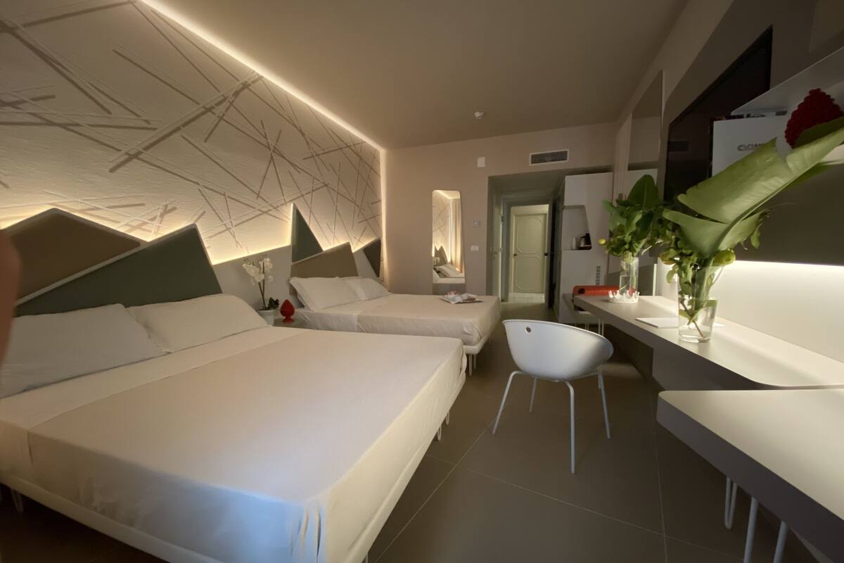 A modern hotel room with two beds, a desk, and a chair.