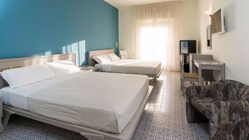 A hotel room with two beds, a TV, a desk, and a patterned chair.