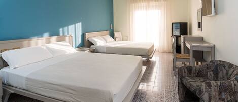 A hotel room with two beds, a TV, a desk, and a patterned chair.