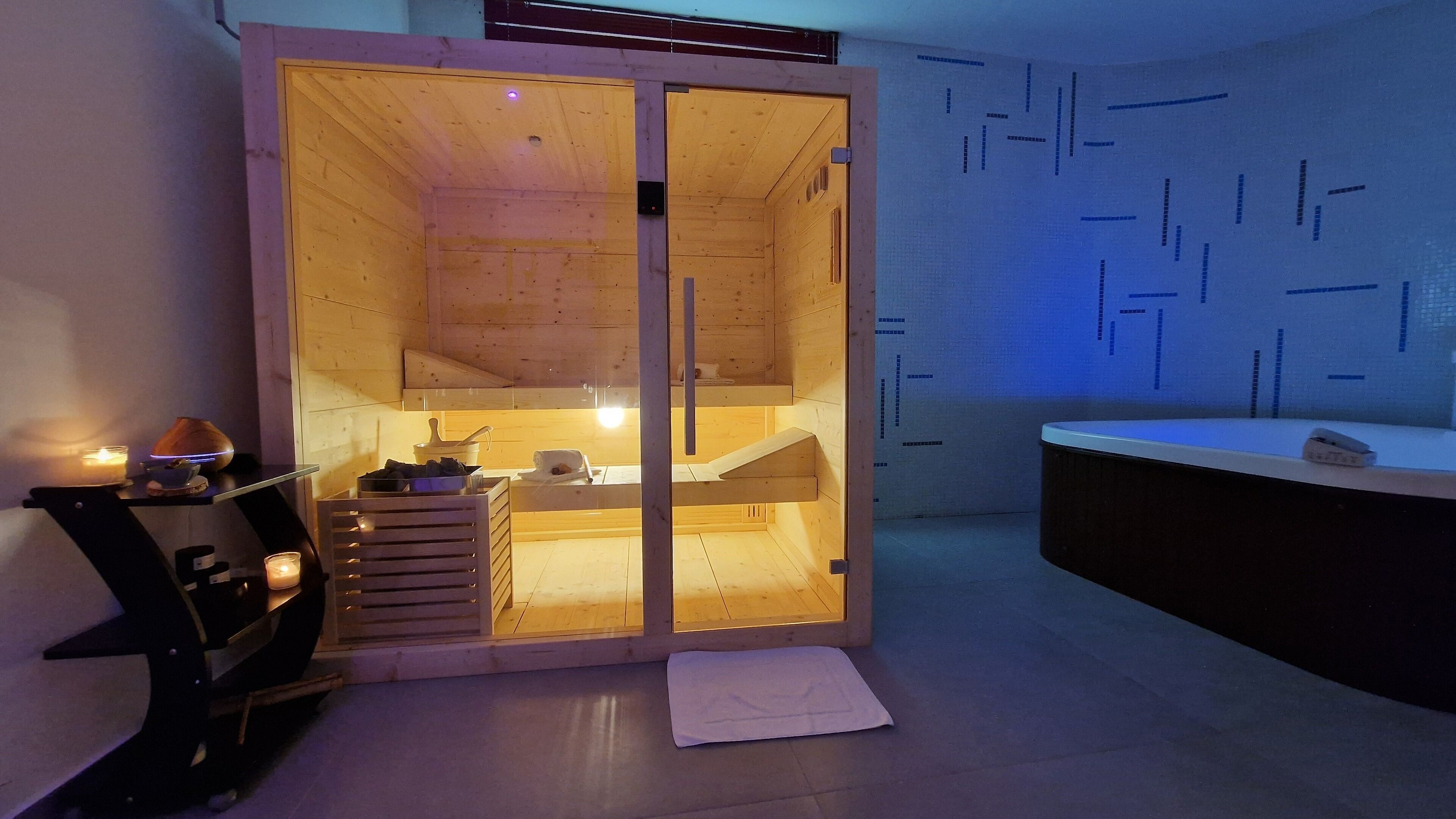 A sauna room with a wooden interior, a sink, and a towel on the floor.
