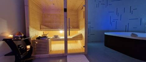 Un cuarto de sauna con paredes de madera, un lavamanos y una toalla en el suelo.